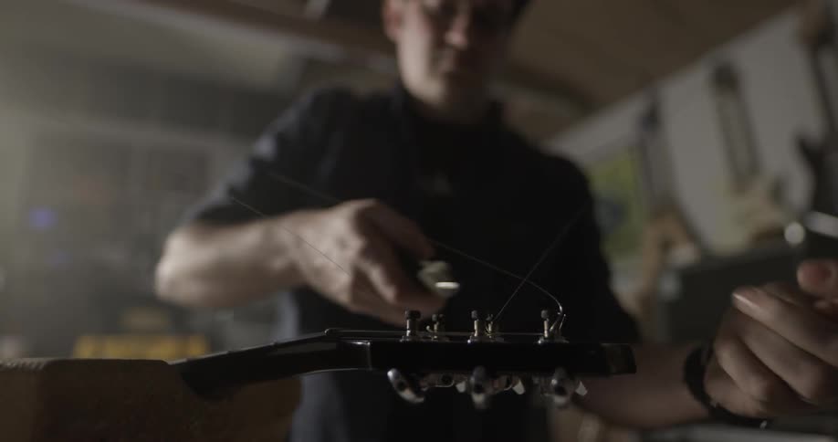 Man cuts excess guitar string from head of guitar