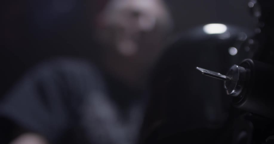 A man turns a key to something in relative darkness with only one light