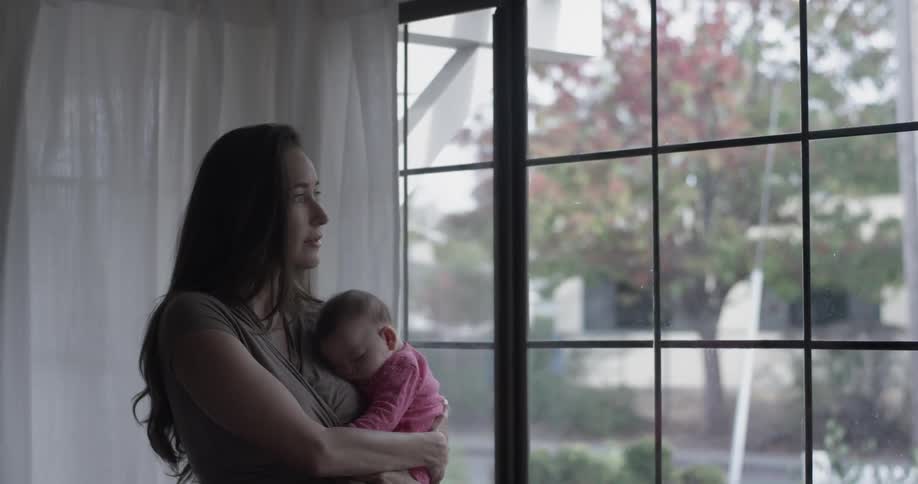 Woman holds baby by window