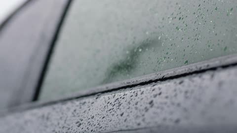 A close up view of a car with raindrops is displayed