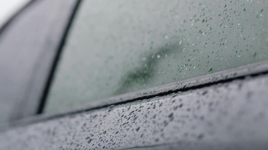 A close up view of a car with raindrops is displayed