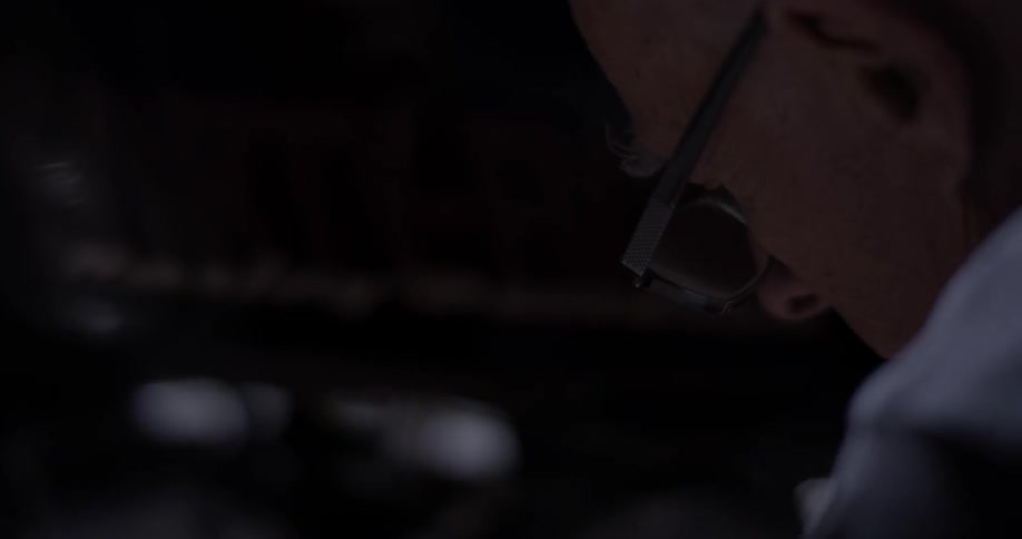 Man works on harley-davidson motorcycle in low light