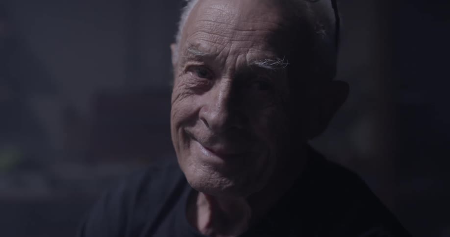 Elderly man looks up and smiles at the camera