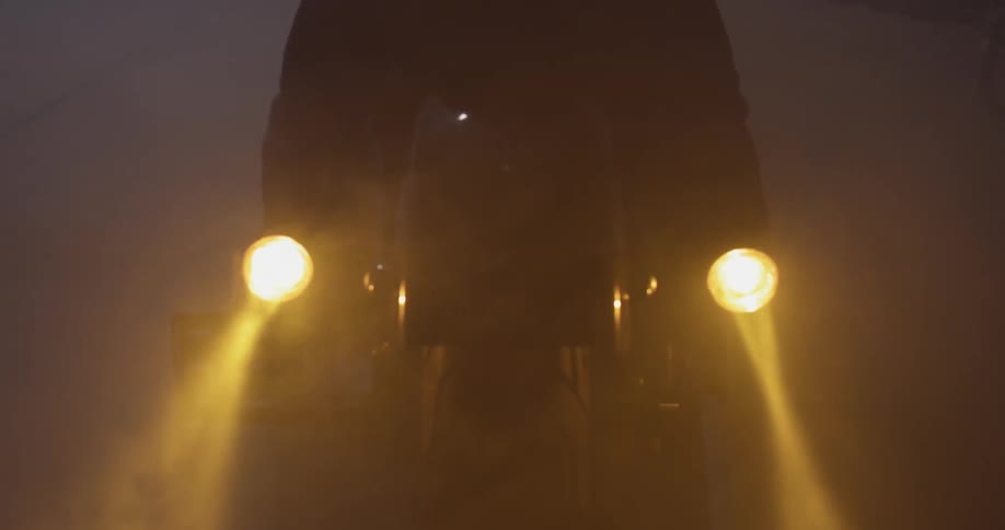 Motorcycle lights shine through the fog