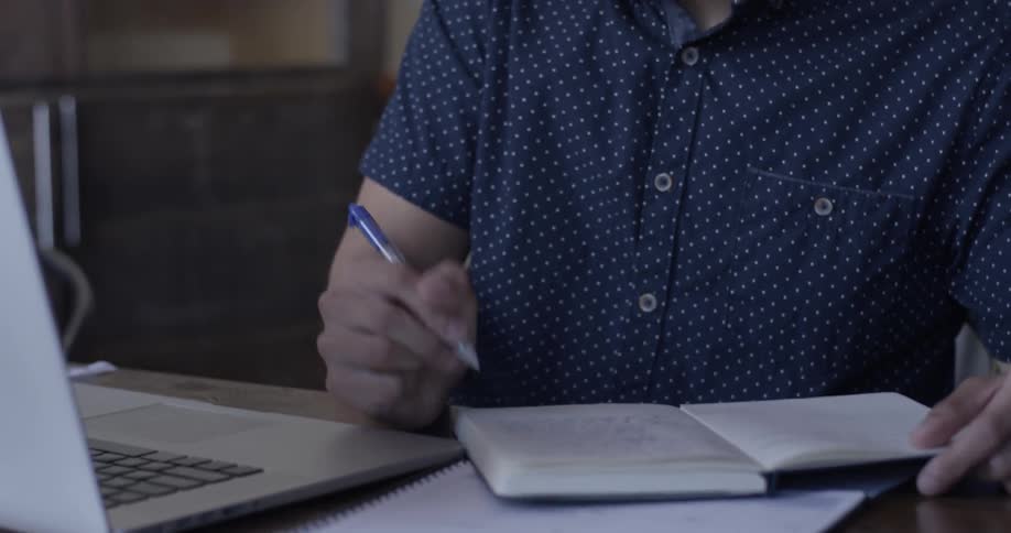 A man writing in a book in a coffee shop