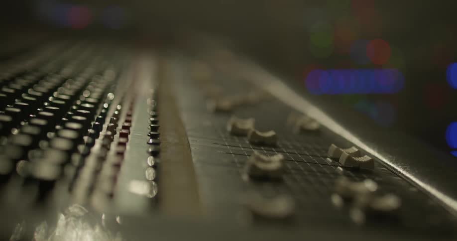 Man adjusts sliders on an audio mixer