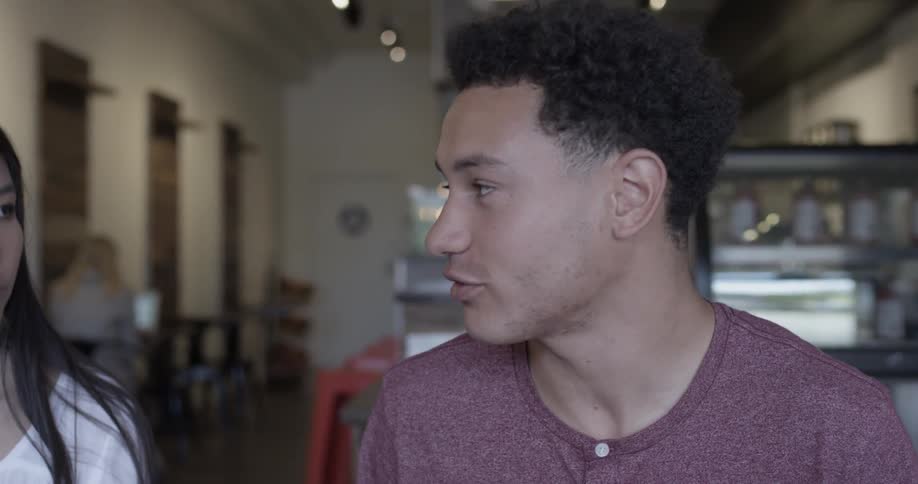 Man talks to other at table in cafe