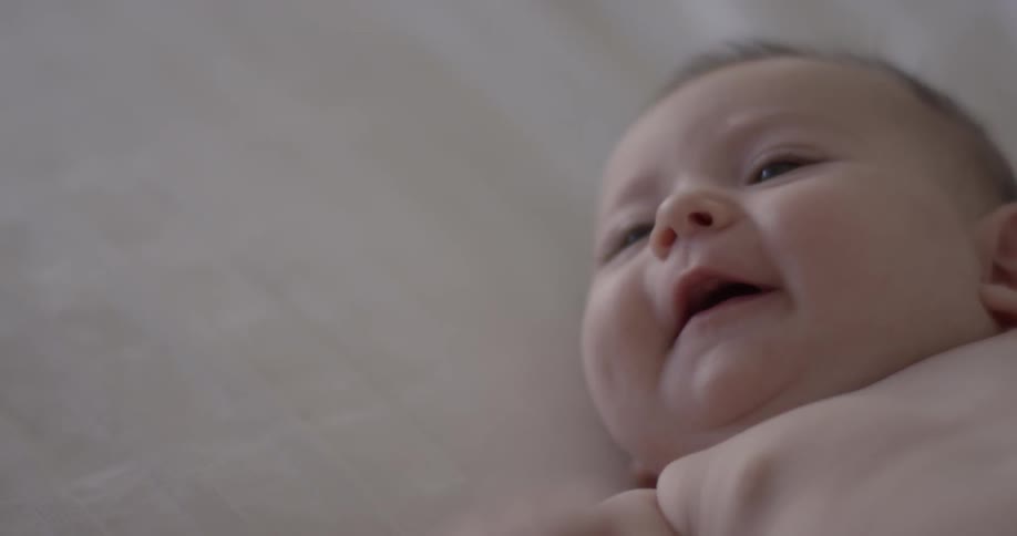Parent holding their baby's finger as baby looks at parent
