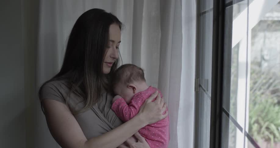 A woman is holding a baby indoors