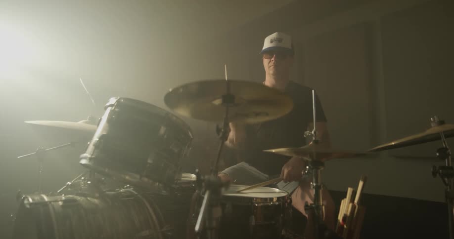 Man plays drums in dimly lit room