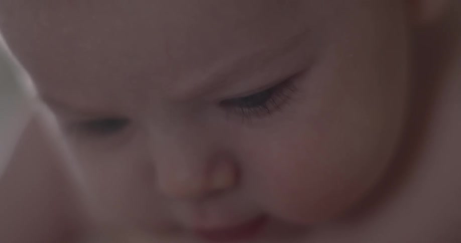 A fat chubby naked baby is squirming around curious about something he is looking at
