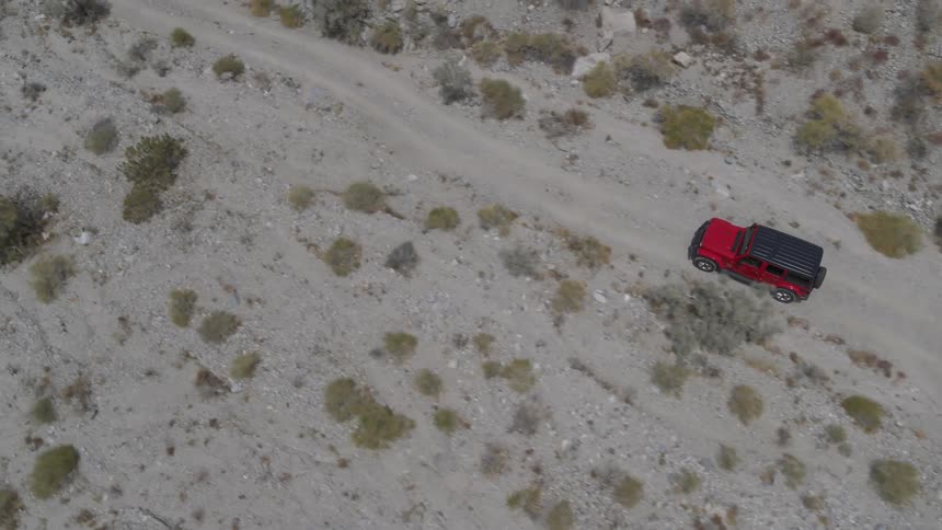 Red car drives on dirt road in the desert