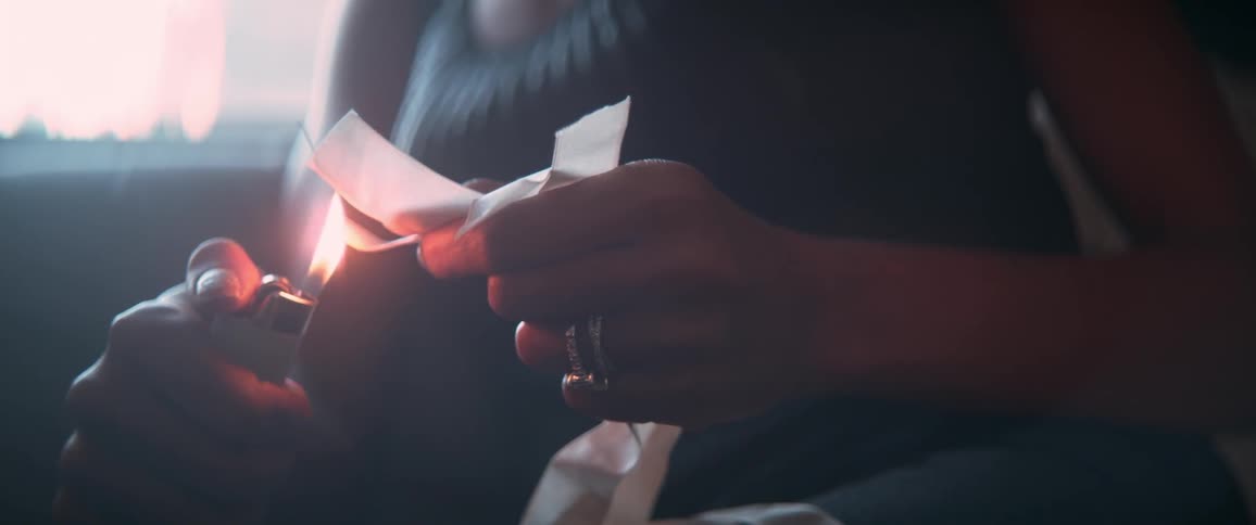 A woman torching the end of ribbons with a lighter
