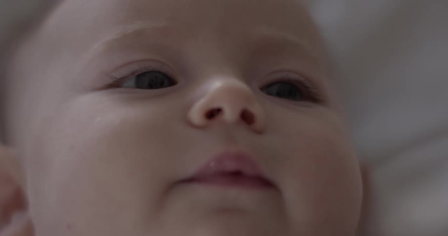 A baby lays on its back as it looks off to the side