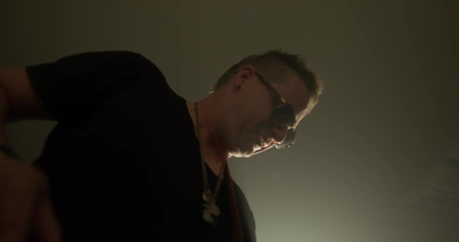 A man expertly plays a bass guitar as a light shines on him