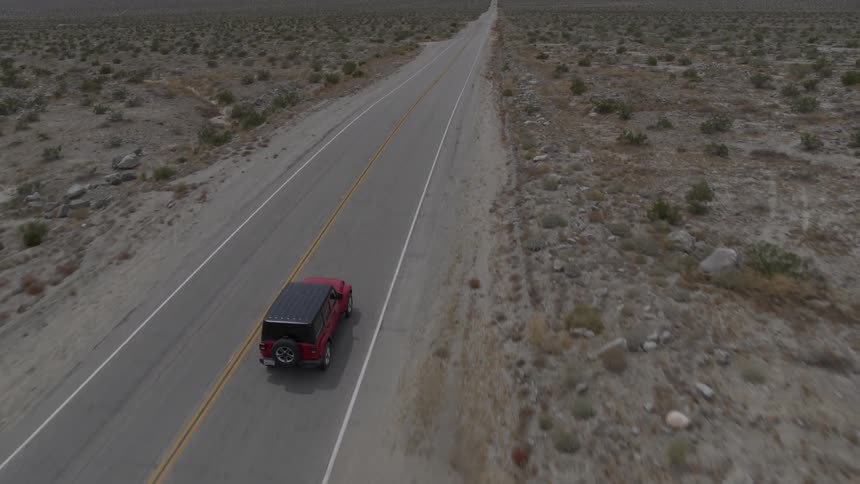 Car drives down road along wasteland
