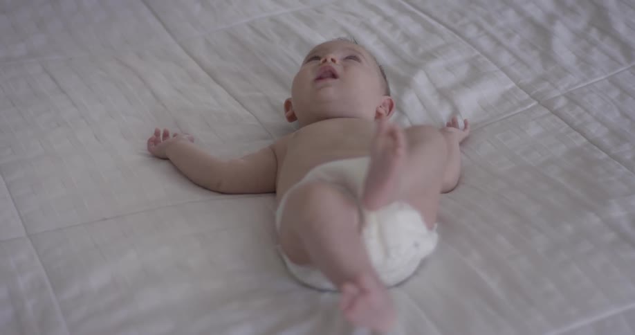 Baby wearing a diaper laying on a bed