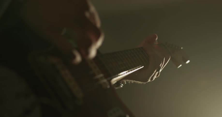 Man playing an electric guitar in a dimly lit room