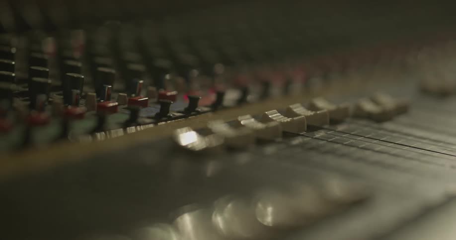A hand moves controls on a soundboard