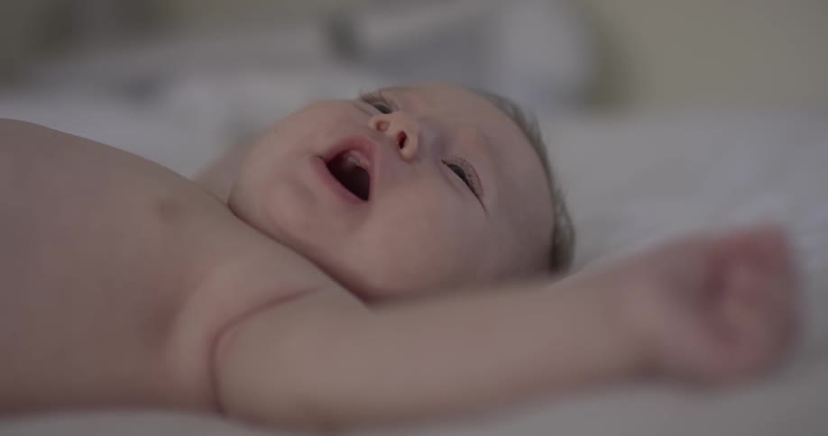 Close up of baby lying on back with arms spread