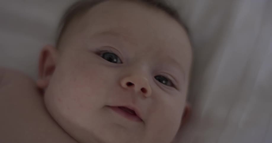 A baby smiles slightly and looks away