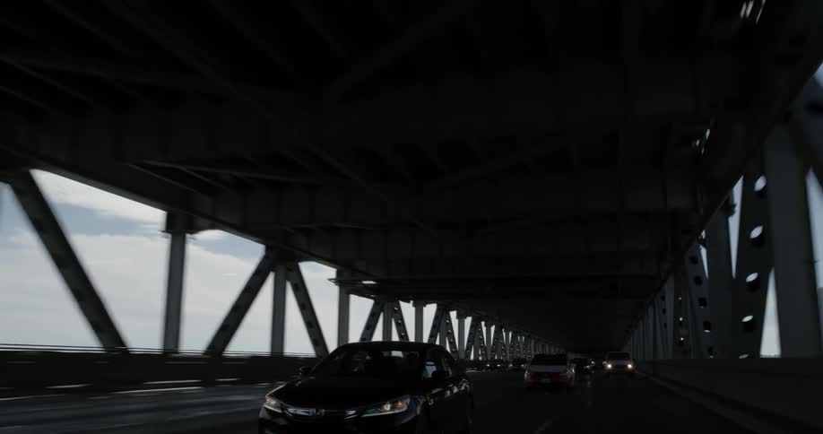 Cars drive along road under a freeway
