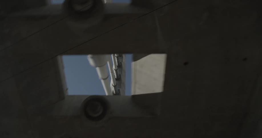 A car drives down the street under a bridge and looks up at tall buildings blue skies with the sun and clouds
