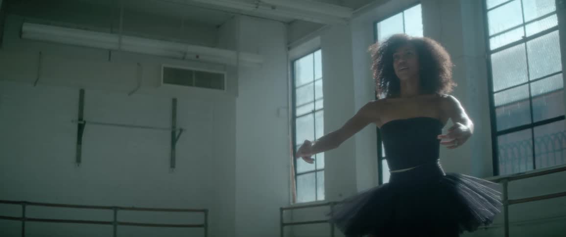 A woman in a black tutu dances in a studio