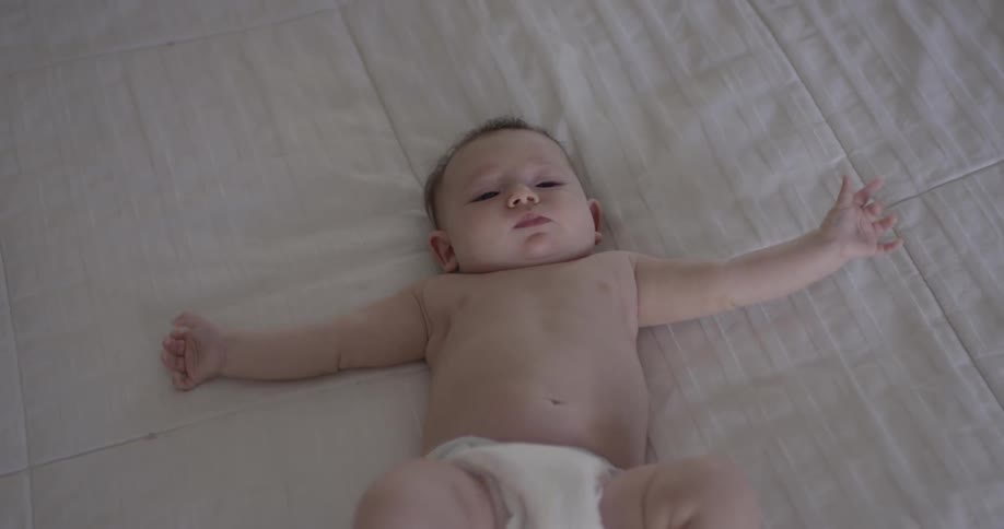 A baby lays on a blanket and wriggles