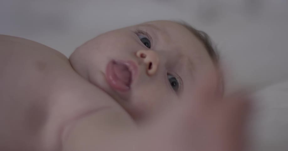 A young baby laying on it's back making faces
