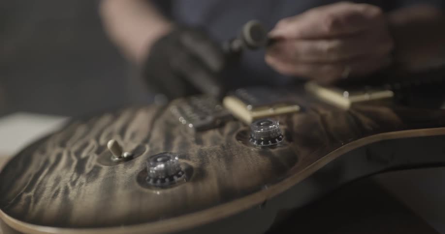 A person using a tool beside a guitar
