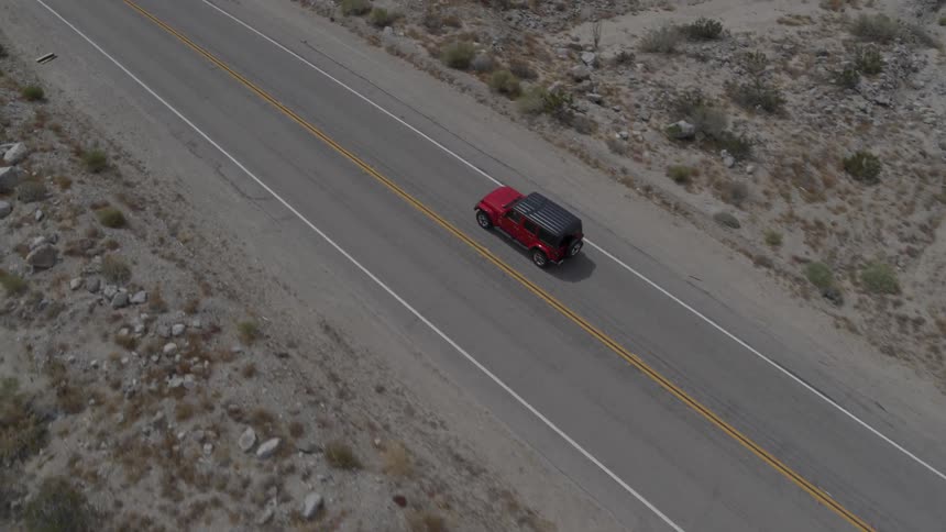 A red vehicle drives down the road