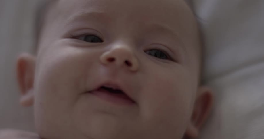 Baby lying his back stares and begins to smile