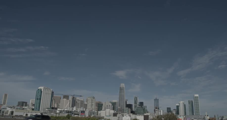 Cars drive down a highway that leads away from a city