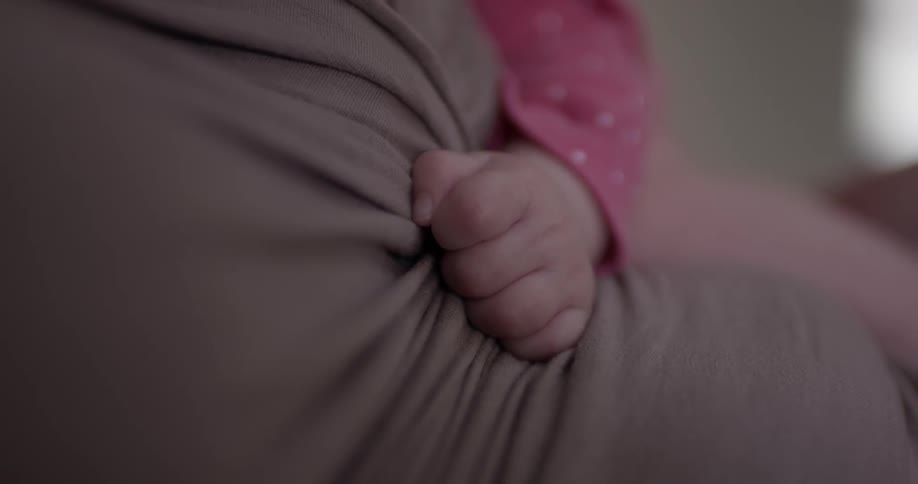 Baby clutches arm of adult