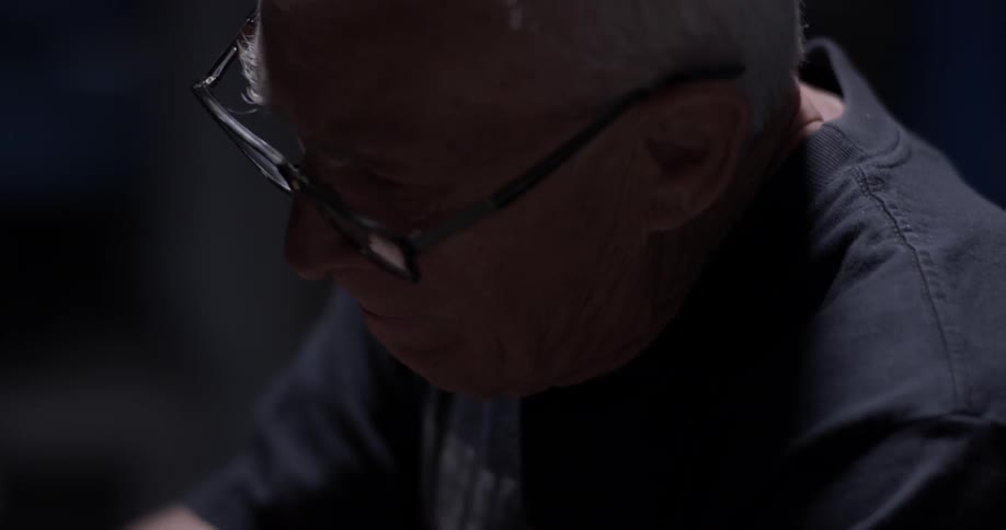 A man wearing glasses works in the darkness