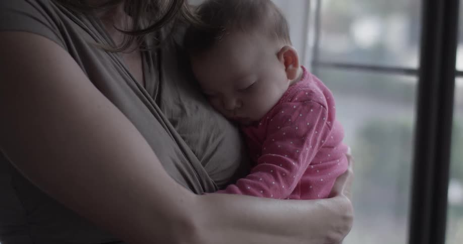 A woman holding an infant by a window