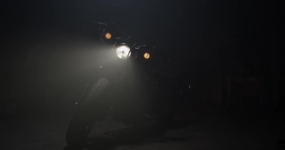 Motorcycle in darkness with front light beaming