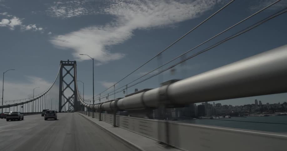 A city on the far side of a suspension bridge draws closer
