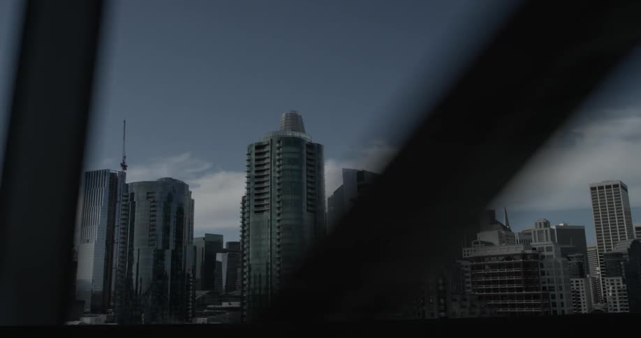 Driving by a major city seen through the metal beams of a bridge on a nice sunny cloudy day