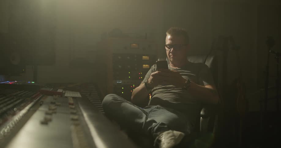A man looks at his phone in a music studio