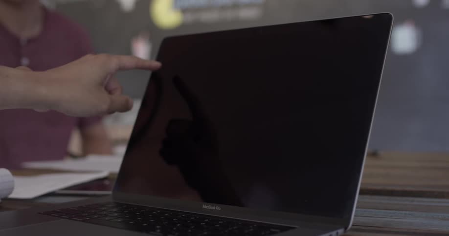 Person points at laptop while off screen