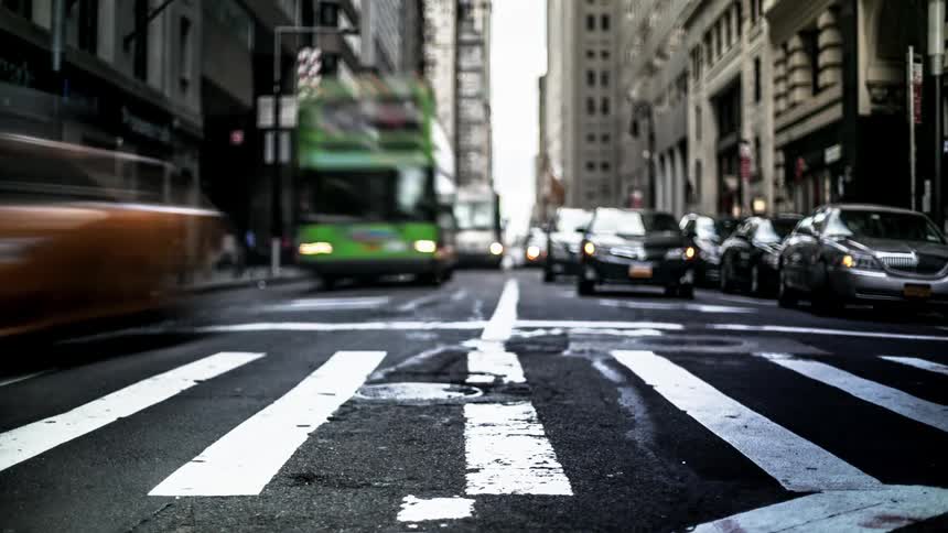 Cars and pedestrians move around intersection in city during day