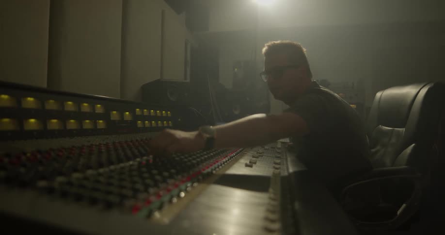 A man adjusts the dials on a music studio panel