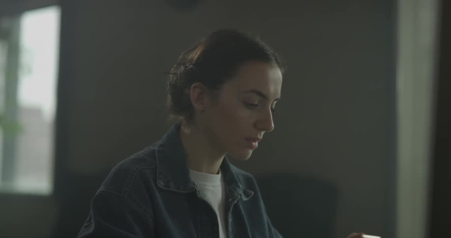 A woman sitting is glancing down at her phone