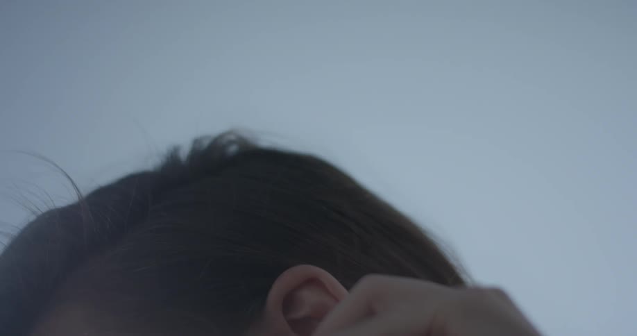 A woman turns around as her hair is blown by the breeze