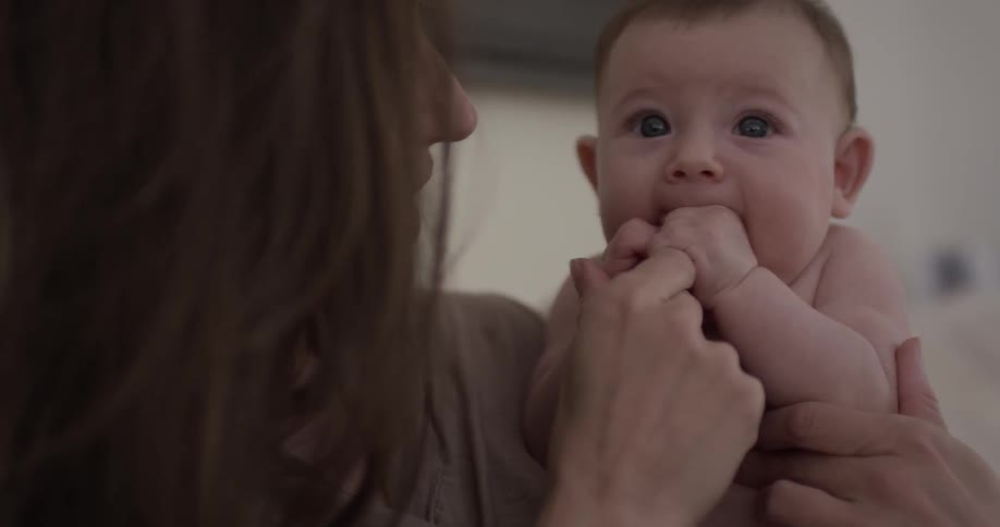 A baby chews on the finger of the woman that is holding it