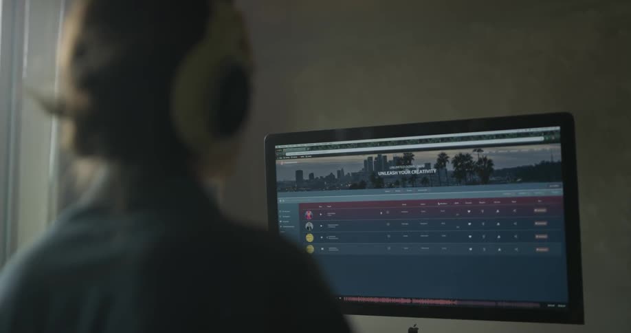 A woman works on a studio computer with headphones on