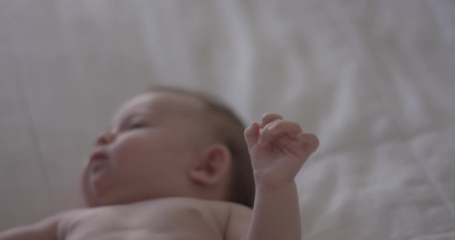 A baby stretches his arms and legs while lying down