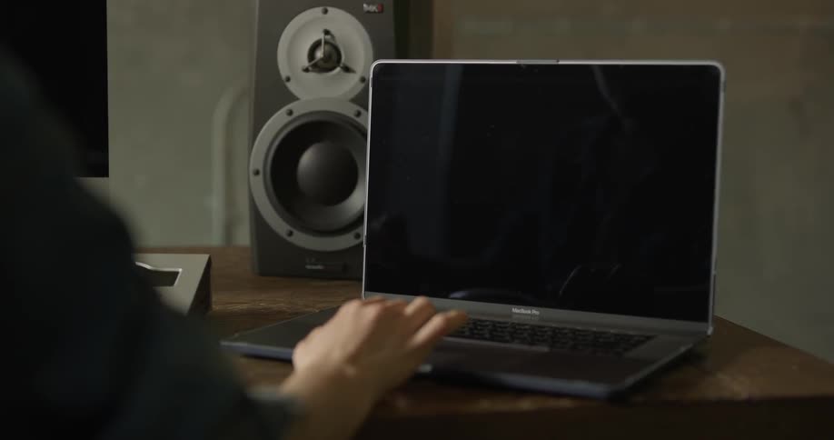 A person types with one hand on a laptop that sits on a desk